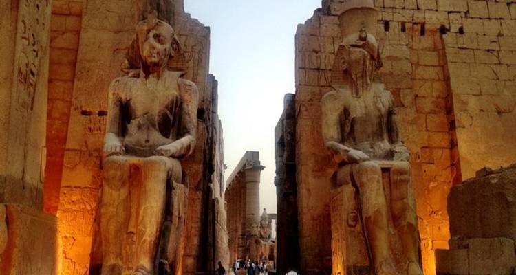 Statues illuminées et structures anciennes au temple de Louxor dans la soirée.
