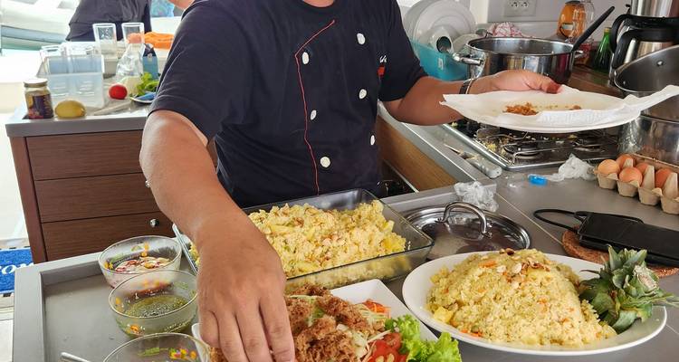 Chef préparant un repas dans une cuisine de yacht avec divers plats.