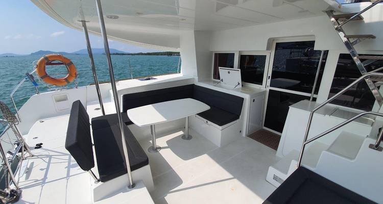 Pont de yacht avec coin salon et salle à manger donnant sur la mer.