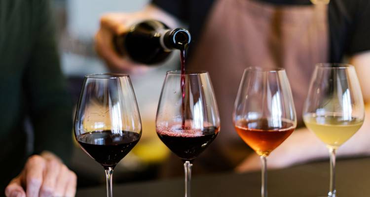 Personne versant du vin dans une rangée de verres.