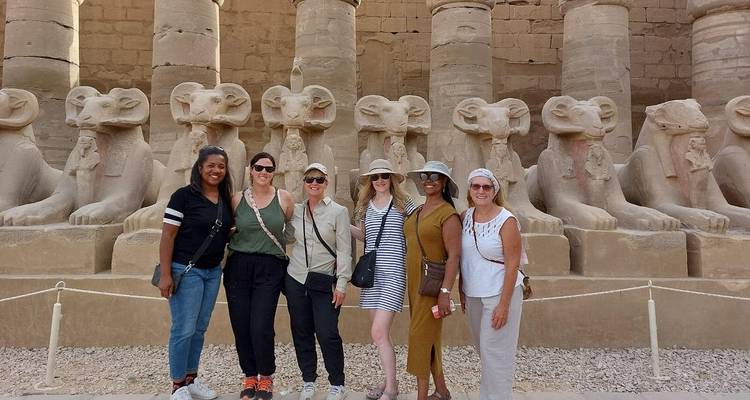Group of people posing in front of ancient statues at a temple site.