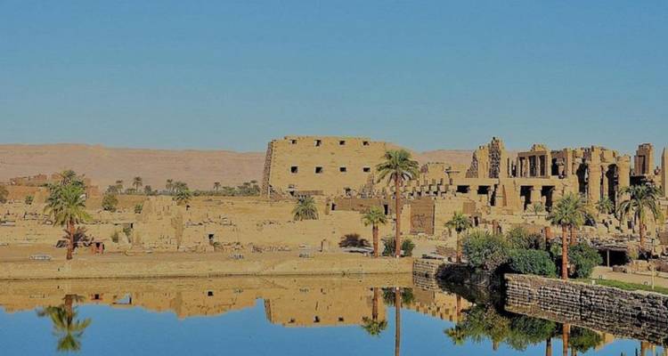 Scenic view of ancient ruins reflected in water with a clear sky.