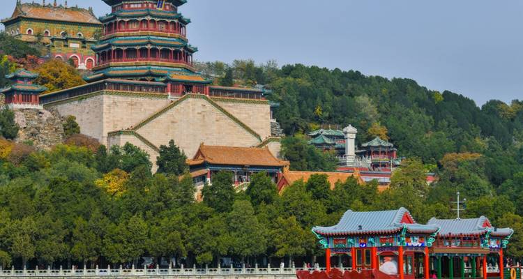 Architecture chinoise traditionnelle avec des toits colorés et une végétation luxuriante.