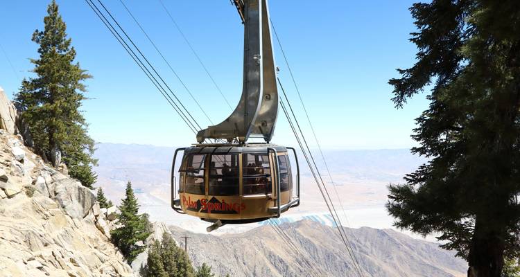 El teleférico de Palm Springs ascendiendo sobre un paisaje rocoso con una vasta vista del desierto.