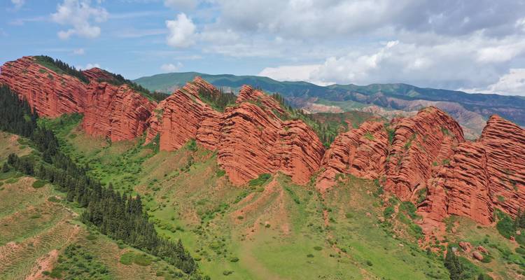 Dramatische rote Felsformationen in einem grünen Tal.
