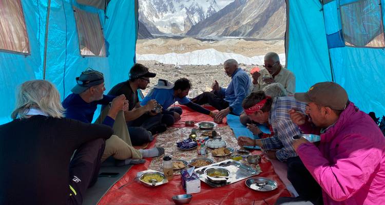 Group enjoying a meal in a tent with mountain views.