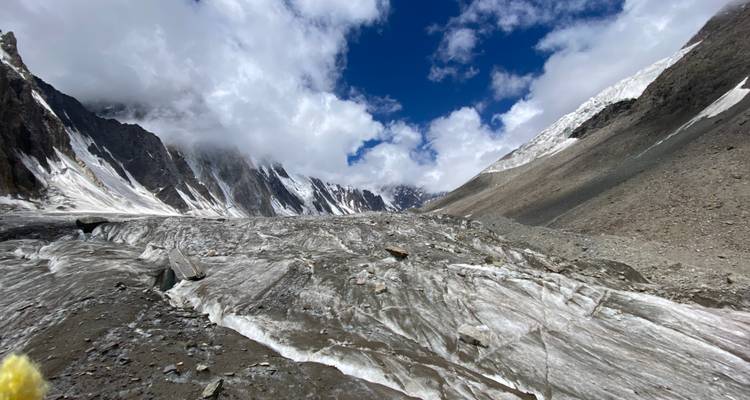 Glacier and mountain landscape under a partly cloudy sky.