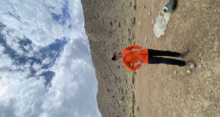 Person standing outdoors with hills behind.