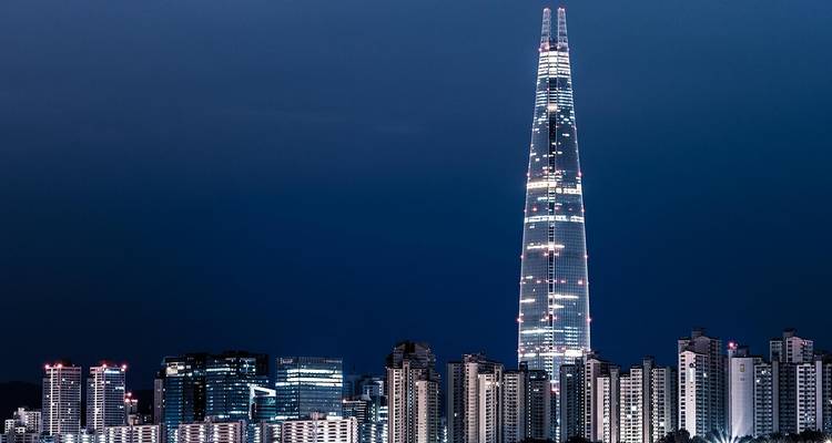 Een moderne wolkenkrabber die 's nachts boven een stadshorizon uittorent.