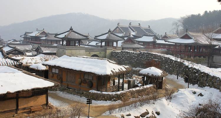 Een met sneeuw bedekt Koreaans dorp met traditionele architectuur.