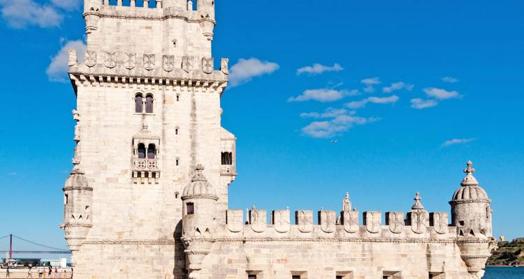 Tour de Belém avec ciel bleu et pont au loin.