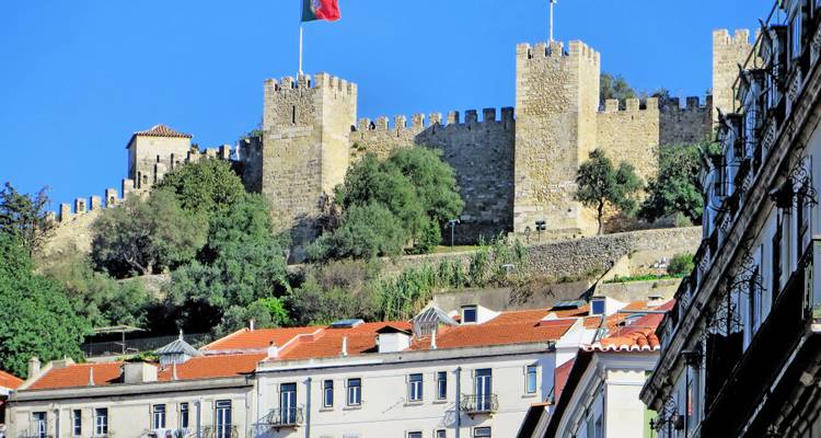 Château sur une colline avec des drapeaux flottant au-dessus.