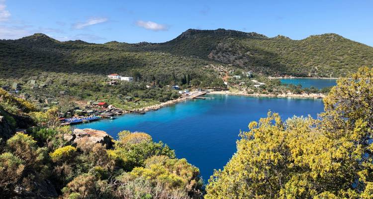Vue panoramique d'une baie turquoise entourée de verdure.