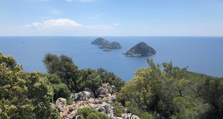 Un trio de petites îles dans l'océan avec un premier plan rocheux.