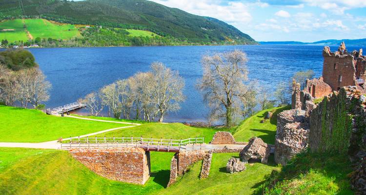 Ruines au bord d'un lac avec des paysages verdoyants et un ciel bleu dégagé