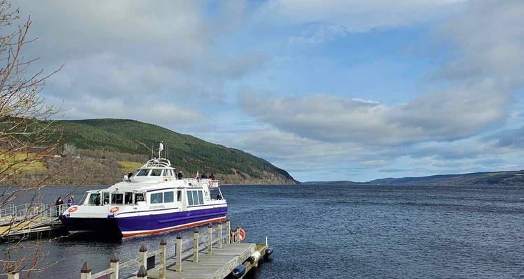 Un bateau amarré à un ponton sur un grand lac avec des collines en arrière-plan