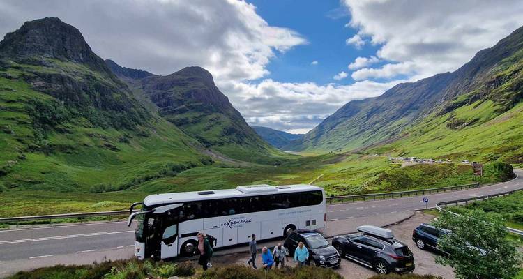 Un groupe de personnes à côté d'un autocar de tourisme garé dans une région montagneuse