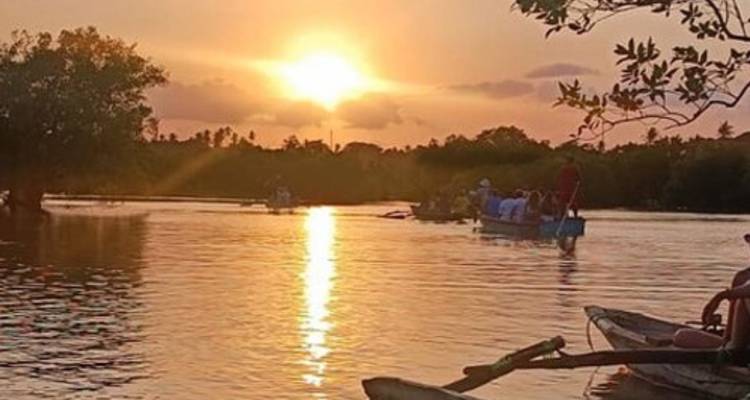 Des gens dans un bateau au coucher du soleil sur une rivière calme