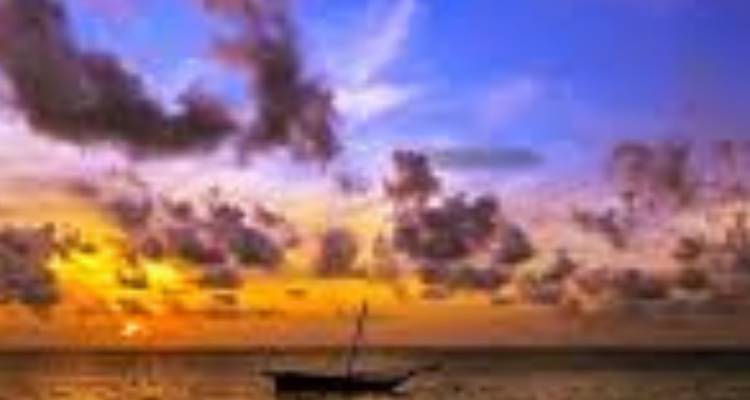 Un coucher de soleil coloré sur l'océan avec un petit bateau en silhouette