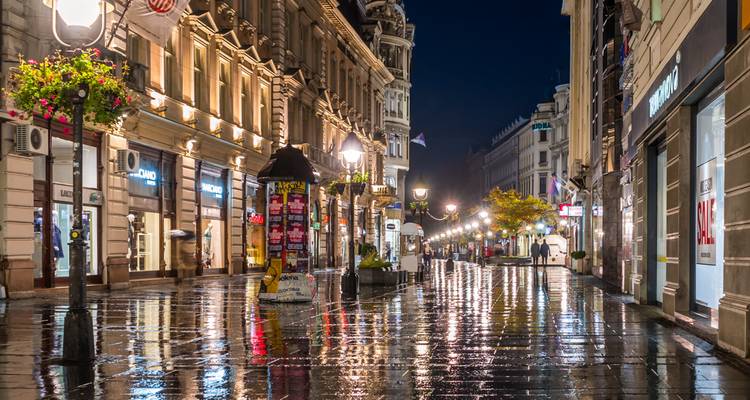 Een regenachtige straat in een levendige binnenstad 's nachts