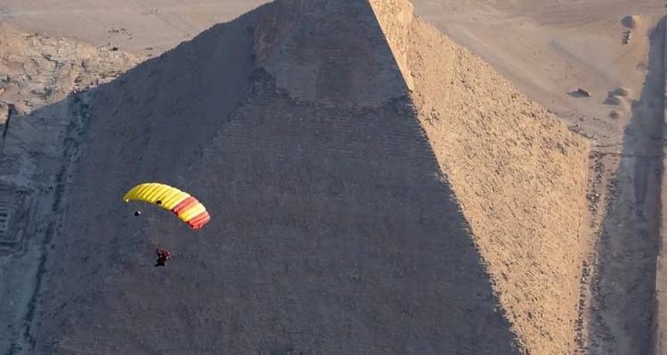 Parachutist die neerdaalt in de buurt van een grote piramide in Egypte.