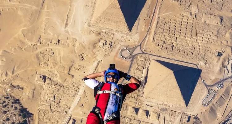 Parachutespringer boven piramides, woestijnlandschap beneden.