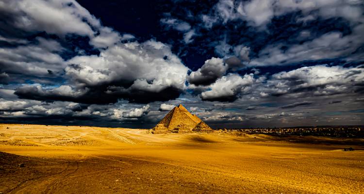 Piramide onder dramatische wolken, woestijn op de voorgrond.