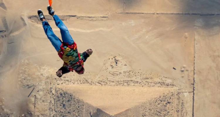 Parachutespringer in vrije val boven woestijn en piramide.