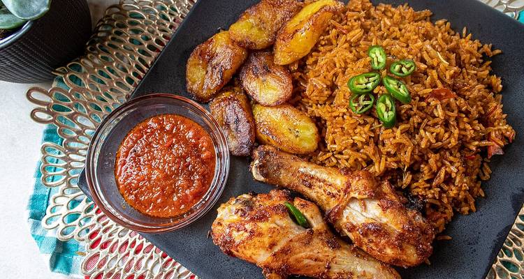 Traditionelle Mahlzeit mit Reis, Kochbananen, Hähnchen und Soße.