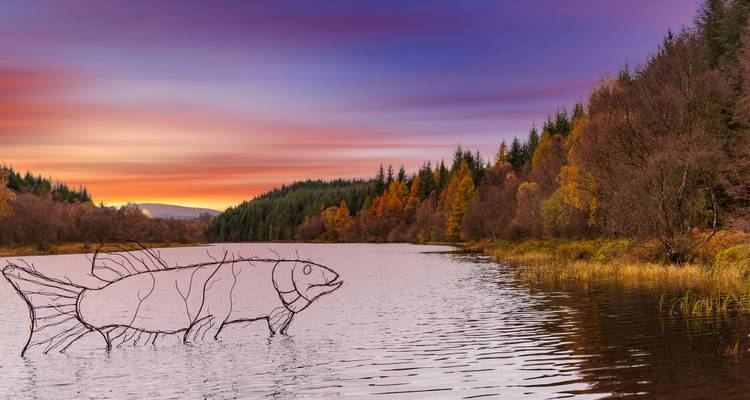 Rivière avec une sculpture de poisson au coucher du soleil.