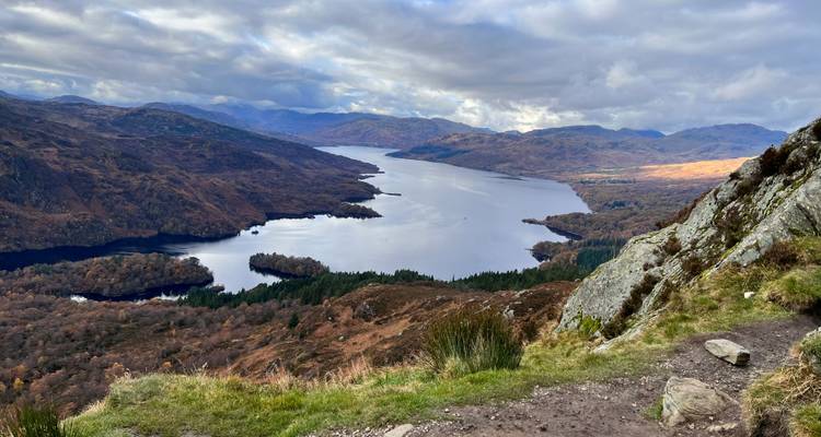 Vue panoramique d'un lac entouré de montagnes et d'un ciel dramatique.