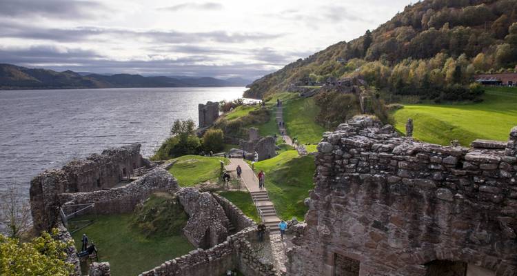 Ruines de château surplombant un lac avec des collines.