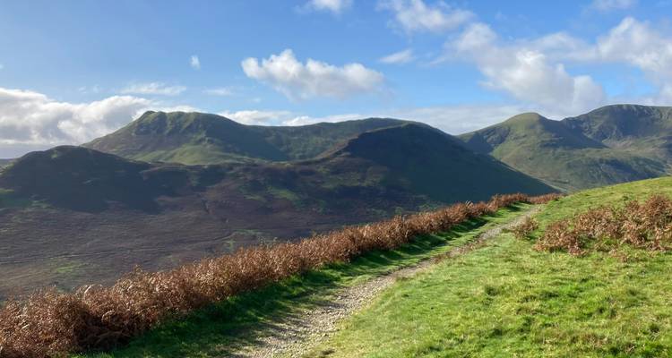 Pathway along grassy hills with mountains.