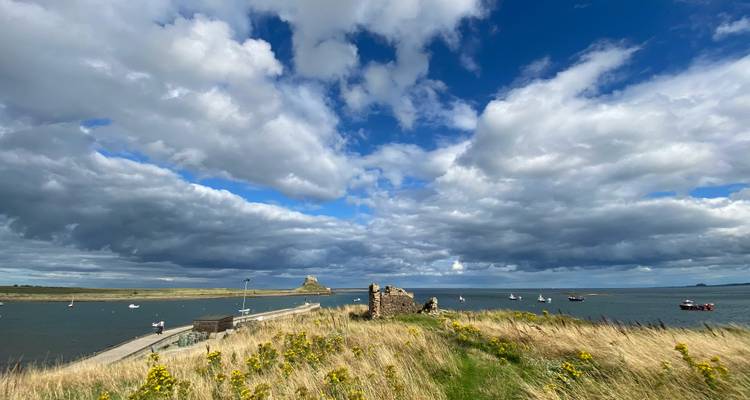 Kustscène met een klein kasteel en boten.