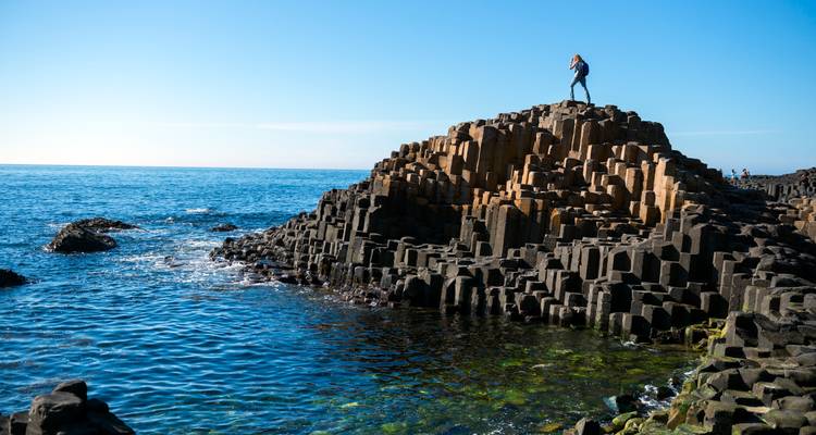 Persoon die staat op de rotsformaties van Giant's Causeway.