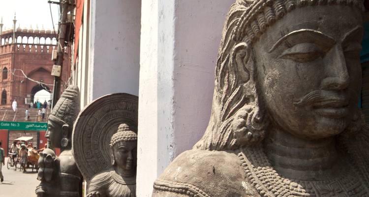 Statues en pierre exposées dans une rue avec l'arche de la Jama Masjid et le trafic des pousse-pousse en arrière-plan