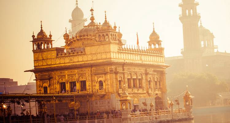 Le Temple d'Or scintillant à la lumière chaude du matin avec des pèlerins rassemblés autour du bassin sacré