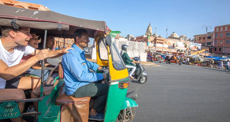Personas disfrutando de un paseo en rickshaw en una calle bulliciosa de la ciudad.