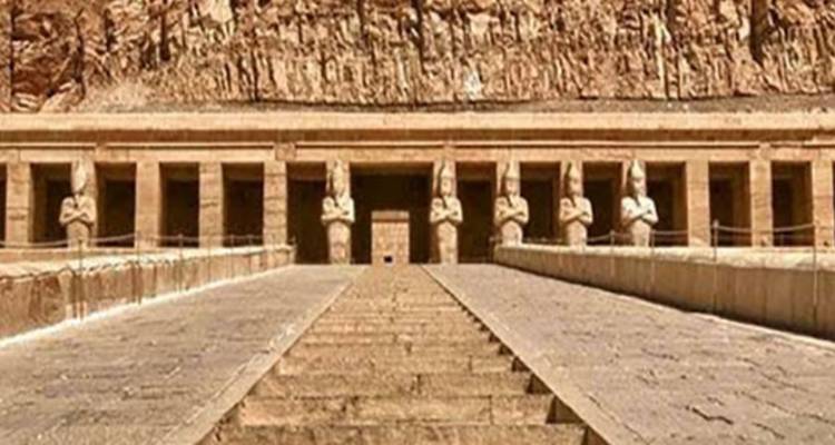 Entrée du temple flanquée de statues, menant à une falaise.