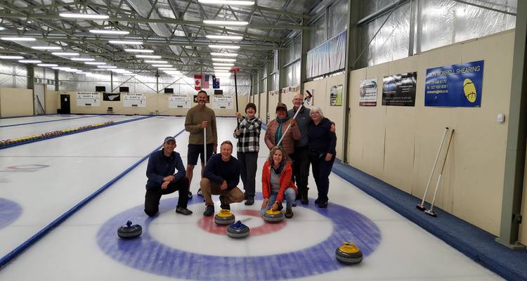 Des personnes qui apprécient une partie de curling sur une patinoire intérieure.