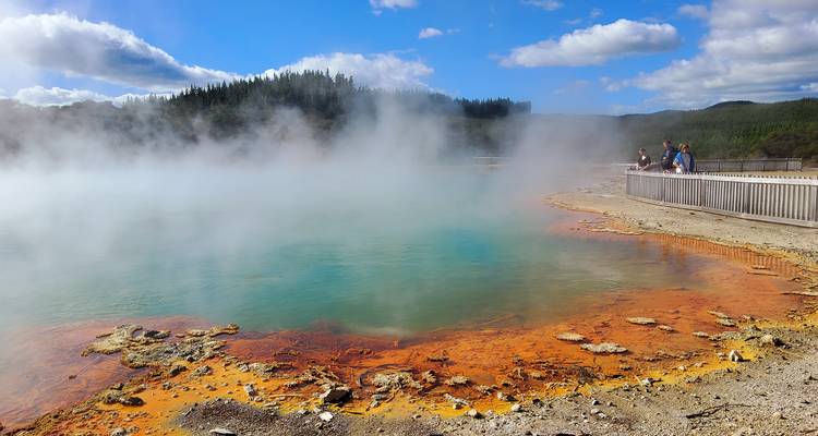 Área geotérmica con agua humeante y minerales coloridos.