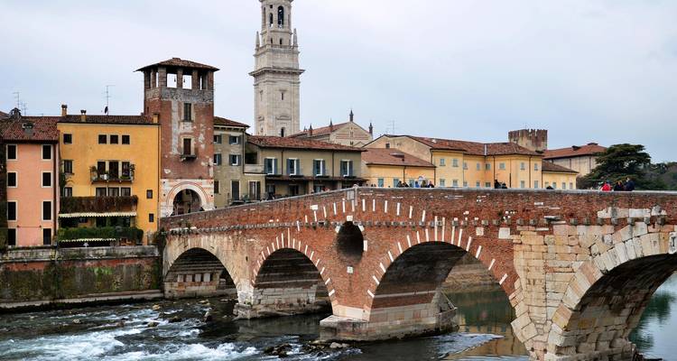 Historic bridge crossing a river with buildings.