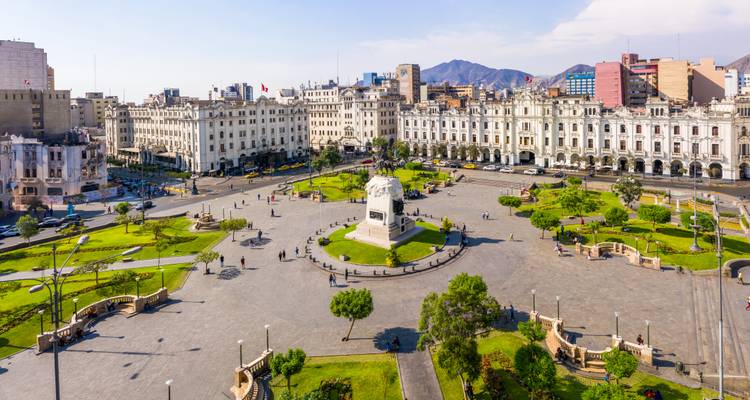 Une grande place avec un monument central et des bâtiments environnants.