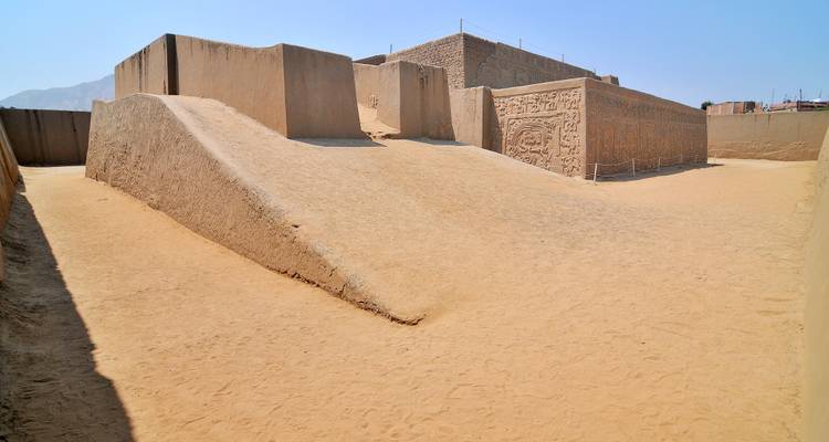 Ruines anciennes avec des motifs sculptés dans un environnement désertique.