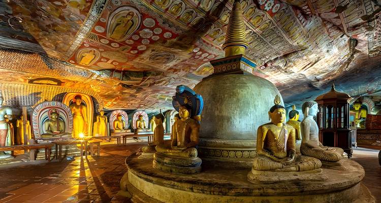 Interieur van een grottempel met Boeddhabeelden en kleurrijke schilderingen.
