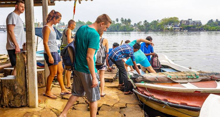 Toergroep die zich voorbereidt om aan boord van kleine boten bij een rivier te gaan.