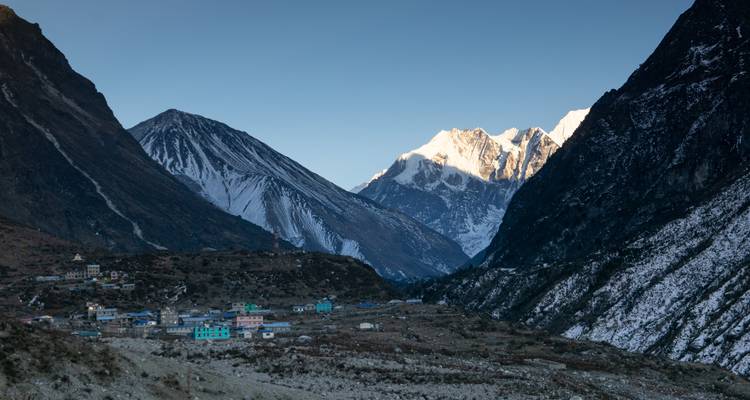 Un village de montagne aux maisons colorées sous des sommets enneigés.