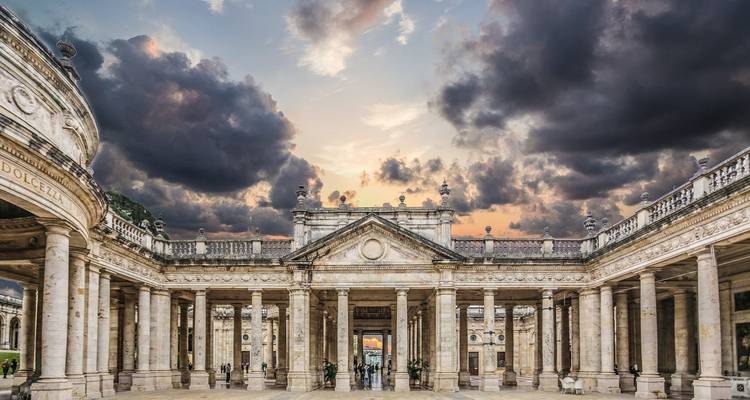 Un grand bâtiment avec des colonnes et un ciel dramatique.