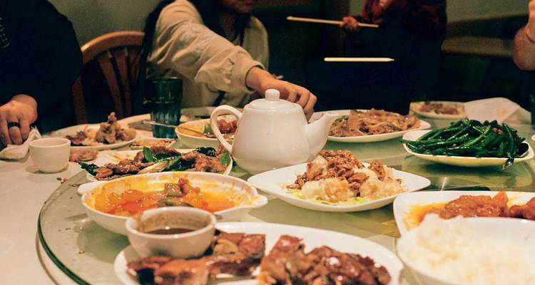 Menschen, die an einem runden Tisch mit einer Auswahl an Gerichten speisen.