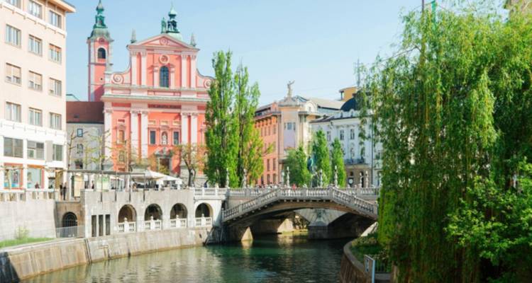 Un río con una iglesia rosa y un puente rodeado de edificios.